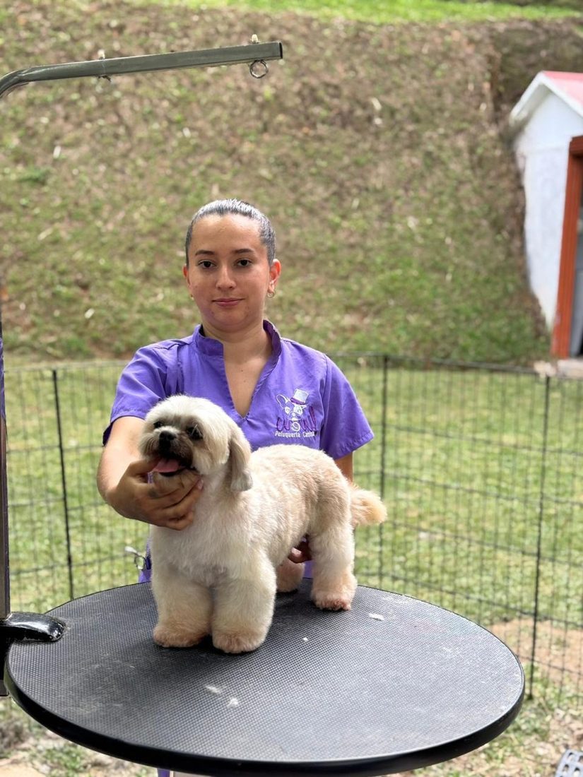 Sandra en la mesa de grooming con un perrito recién bañado